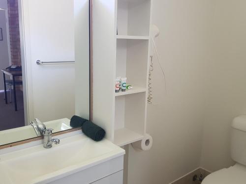 a bathroom with a toilet, sink, and mirror at Kipparing Village Motel in Redcliffe