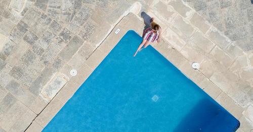 a woman is jumping into a pool of water at Finca Agroturismo Son Menut in Felanitx