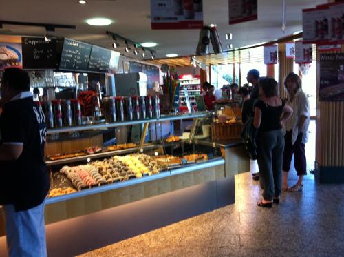 a group of people standing in a food store at Motel de la Gruyère Restoroute in Avry devant Pont