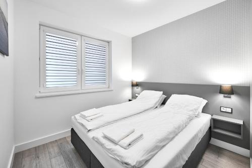 um quarto com uma cama com lençóis brancos e uma janela em Apartamenty Między Jeziorami em Olsztyn
