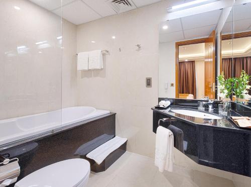 a bathroom with a tub and a toilet and a sink at Mercury Boutique Hotel & Apartment Da Nang in Danang