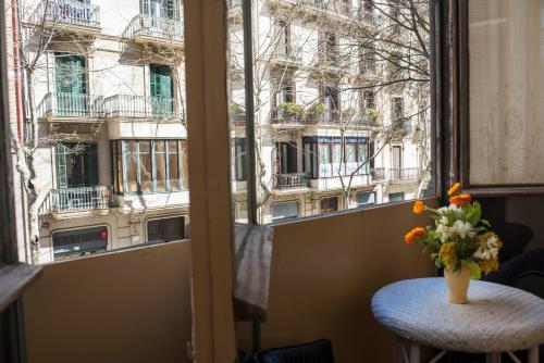 a vase of flowers on a table in front of a window at Fashion House in Barcelona