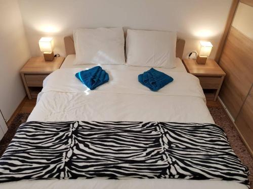 a large white bed with two blue pillows on it at Apartmani F&A in Zlatibor