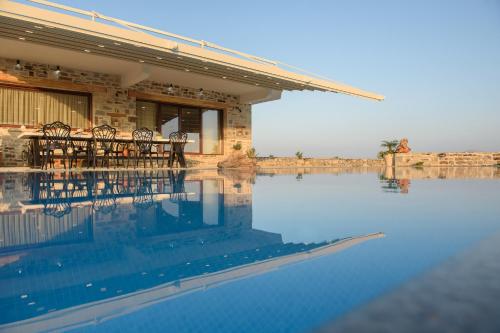 a pool of water with tables and chairs next to a building at Zeus & Dione Luxury Villa in Lagolíon