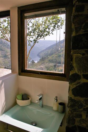 a bathroom with a sink with a window above it at Cabo Do Mundo Casa Rural in Chantada