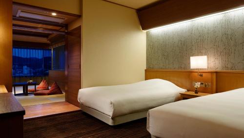 a hotel room with two beds and a window at Laforet Ito Onsen Yunoniwa in Ito