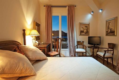 a bedroom with a bed and a desk and a television at Korina Gallery Hotel in Vathi
