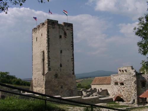 an old castle with two flags on top of it at Hétkanyar Vendégház in Nagyvázsony