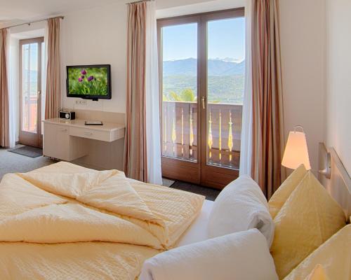 a bedroom with a bed and a tv and a balcony at Pension Christl in Caldaro