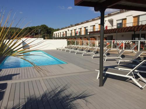 a row of lounge chairs on a patio with a pool at Adonis Aix en Provence in Aix-en-Provence