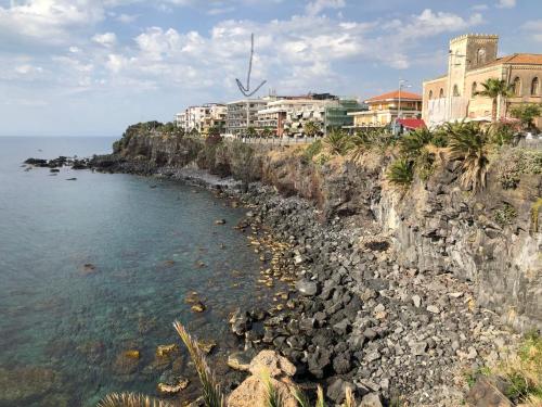 a rocky shore with buildings and the ocean at Casa Vitale in Aci Castello