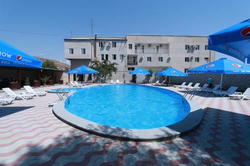 una gran piscina con sombrillas y sillas azules en White House Hotel, en Ereván