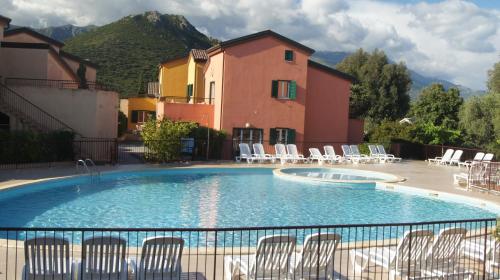 une grande piscine avec des chaises et un bâtiment dans l'établissement Lozari Beach, à Belgodère