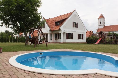 uma casa com piscina em frente a uma casa em Hétkanyar Vendégház em Nagyvázsony