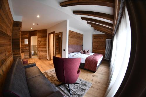 a bedroom with a bed and a couch in a room at Hotel Alpenrose Wellness in Vattaro