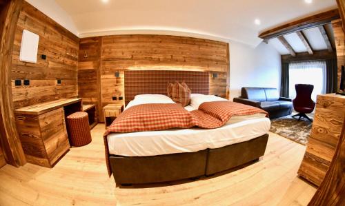 a bedroom with a large bed and a desk at Hotel Alpenrose Wellness in Vattaro
