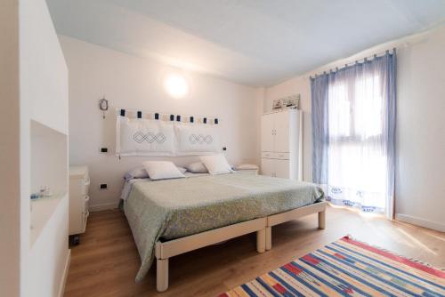 a white bedroom with a bed and a window at Villa Giù Luxury - The House Of Travelers in Faggeto Lario 