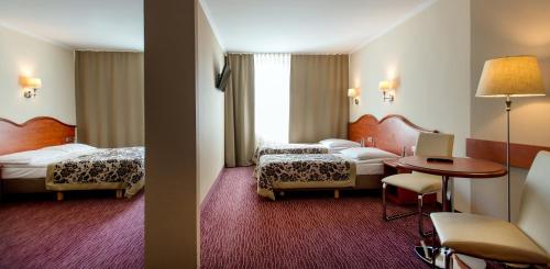クラクフにあるホテル クラクスのベッド2台とテーブルが備わるホテルルームです。