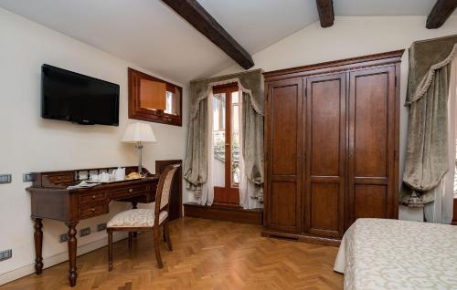 um quarto com uma secretária, uma cama e uma televisão em Hotel Dell'Opera em Veneza