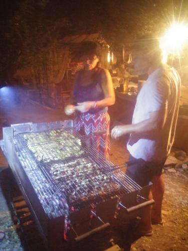 a man and a woman cooking food on a grill at Anatoli Hotel in Agia Marina Aegina