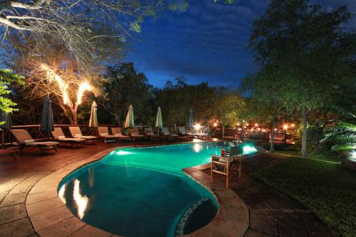 a swimming pool at night with chairs and umbrellas at Grand Kruger Lodge and Spa in Marloth Park