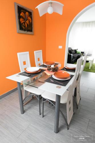 a dining room table and chairs with an orange wall at Emerald Soca Apartment in Tolmin