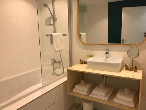 a bathroom with a sink and a shower and a mirror at Hôtel Café Miramar in Le Grau-du-Roi