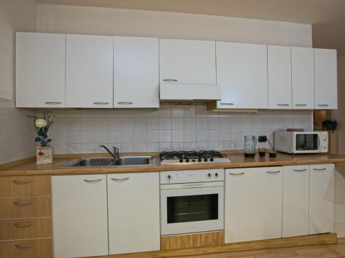 a kitchen with white cabinets and a sink and a microwave at Belvilla by OYO Fiamme in Predazzo