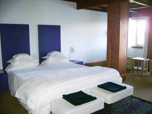 a bedroom with a large white bed with two stools at Hostería Isla Victoria Lodge in Isla Victoria