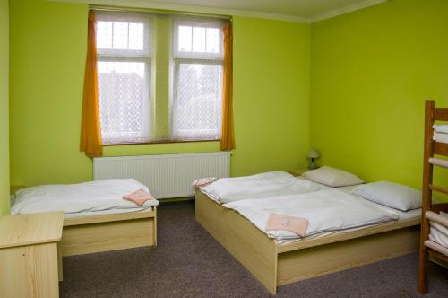 dwa łóżka w zielonym pokoju z dwoma oknami w obiekcie Hotel Modrá hvězda Sadská w mieście Sadská