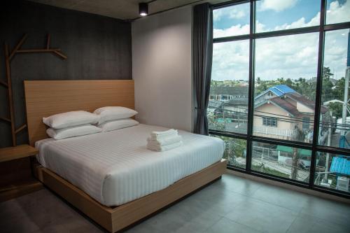a bedroom with a bed and a large window at M1 Hotel in Nakhon Si Thammarat