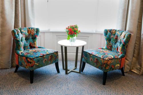 two chairs and a table with a vase of flowers at Sea Spray Hotel in Brighton & Hove