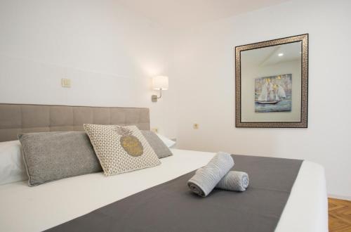 a bedroom with a white bed with pillows and a mirror at Palace apartment in Split