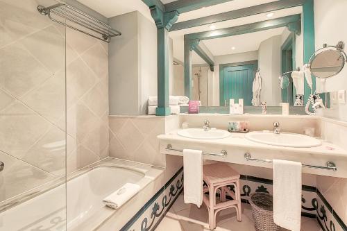 een badkamer met 2 wastafels, een bad en een spiegel bij Hotel LIVVO Volcán Lanzarote in Playa Blanca