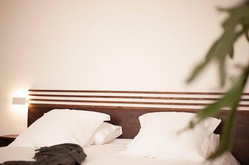 a bed with white pillows and a wooden headboard at Casa Boumort in Sant Marti de Canals