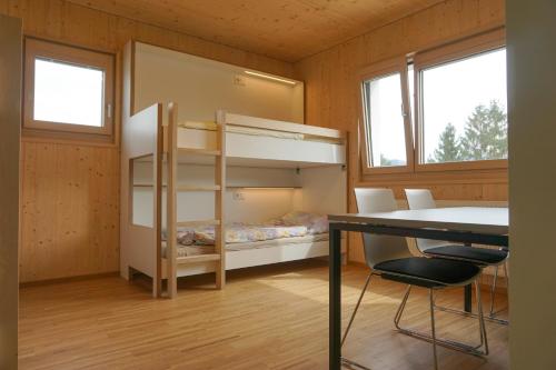 a bedroom with a bunk bed and a desk and two windows at Hostel Salzburg-Wals in Salzburg