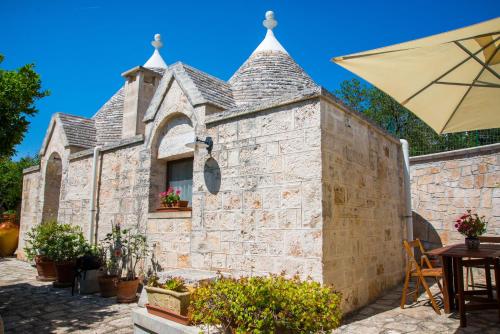 a stone building with a table and an umbrella at Giardino Segreto in Putignano