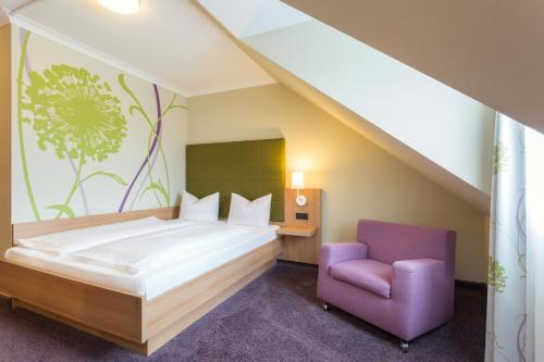 a bedroom with a bed and a purple chair at Hotel - Restaurant Erich Rödiger in Bad Staffelstein