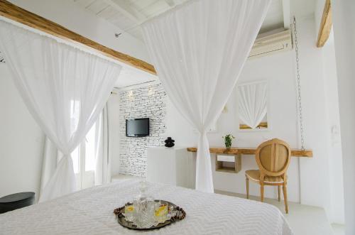 um quarto branco com uma cama com cortinas brancas em Levantes Ios Boutique Hotel em Mylopotas