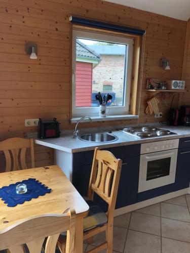 a kitchen with a sink and a stove and a table at Ostseebungalow-Peters in Börgerende-Rethwisch