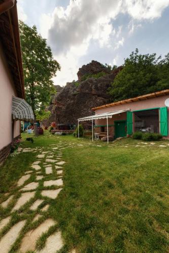 a grass yard with a house and a mountain at Villa Kada in Belogradchik