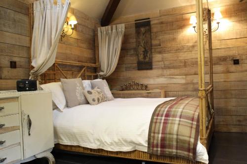 a bedroom with a white bed and wooden walls at The Devils Cradle in Farnham