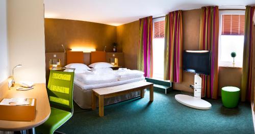 a bedroom with a bed and a desk and a television at Sonn'Idyll Hotel & Saunalandschaft in Rathenow