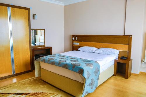a bedroom with a bed with a wooden headboard at Perla Hotel in Dikili