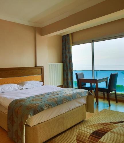 a bedroom with a bed and a table and chairs at Perla Hotel in Dikili