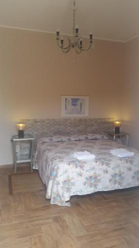 a bedroom with a bed and two tables and a chandelier at Barbara B&B in Fontane Bianche