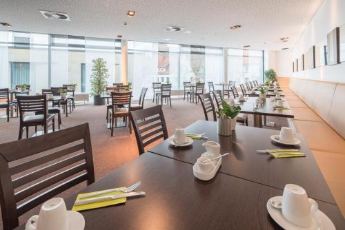 a dining room with tables and chairs and windows at Best Western Plus Hotel Ostertor in Bad Salzuflen
