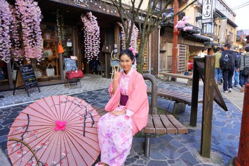 a woman sitting on a bench next to an umbrella at Morizuya in Toyooka