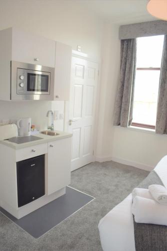 a white kitchen with a sink and a microwave at Kelpies Serviced Apartments in Falkirk