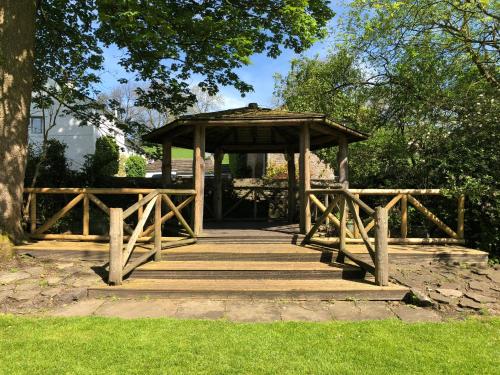 a wooden gazebo in a park with a tree at Calf's Head Hotel in Clitheroe